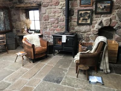 Two armchairs and a fireplace on a stone floored bothy
